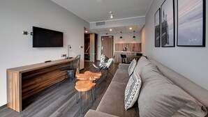Uma sala de estar moderna com sofá, mesa de centro de madeira e televisão.