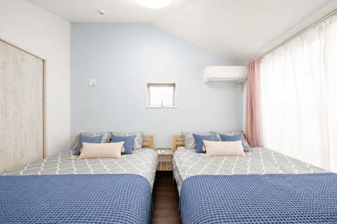 A bedroom with two beds, a window, and an air conditioning unit.