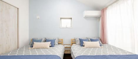 A bedroom with two beds, a window, and an air conditioning unit.