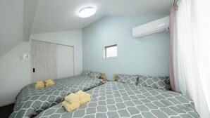 A bedroom with two beds, a small window, and an air conditioning unit. - Higashi Rokugou Black by Tranova (Tokyo)