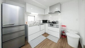 A modern kitchen with white cabinets, stainless steel appliances, and a built-in oven. - Higashi Rokugou Black by Tranova (Tokyo)