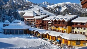 A snow-covered mountain resort with multi-story buildings, ski slopes, and a clear blue sky. - Club Med Valmorel (Les Avanchers-Valmorel)
