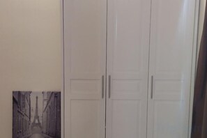 Une armoire blanche fermée, à deux portes, et une petite photo encadrée représentant une scène de rue.