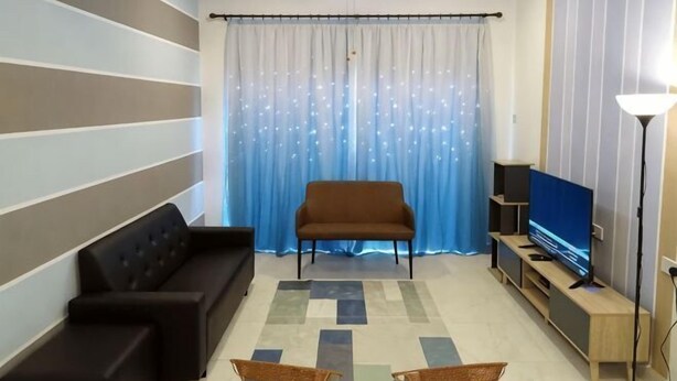 A living room with a sofa, a television, a floor lamp, and a patterned rug. - Sweet home Ch 1 (Tanah Rata)