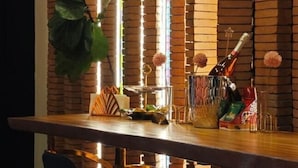 A bar area with a brick wall, a wooden bar counter, and a potted plant. - DAY & NIGHT by THE MOMENT (Chiang Mai)
