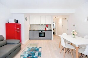 Un espacio habitable compacto con kitchenette, comedor y sofá.