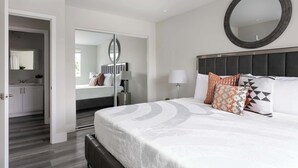 Et moderne hotelværelse med en stor seng, et rundt spejl og udsigt til det tilstødende badeværelse.