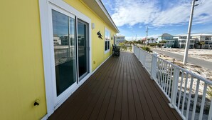 A yellow building with a wooden deck and white railing. - Seaside Bungalow 1 Bedroom Home (Navarre)