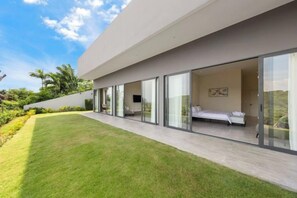 Una casa moderna con un amplio ventanal que da a un dormitorio con cama y televisor.