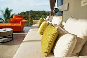 A modern living room with a sofa, a round coffee table, and an orange armchair. - THE GREEN LOTUS SAMUI (Koh Samui)