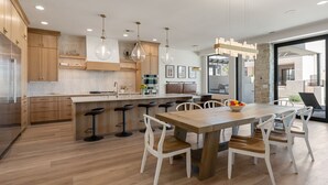A modern kitchen with wooden cabinets, a central island with bar stools, and pendant lighting.