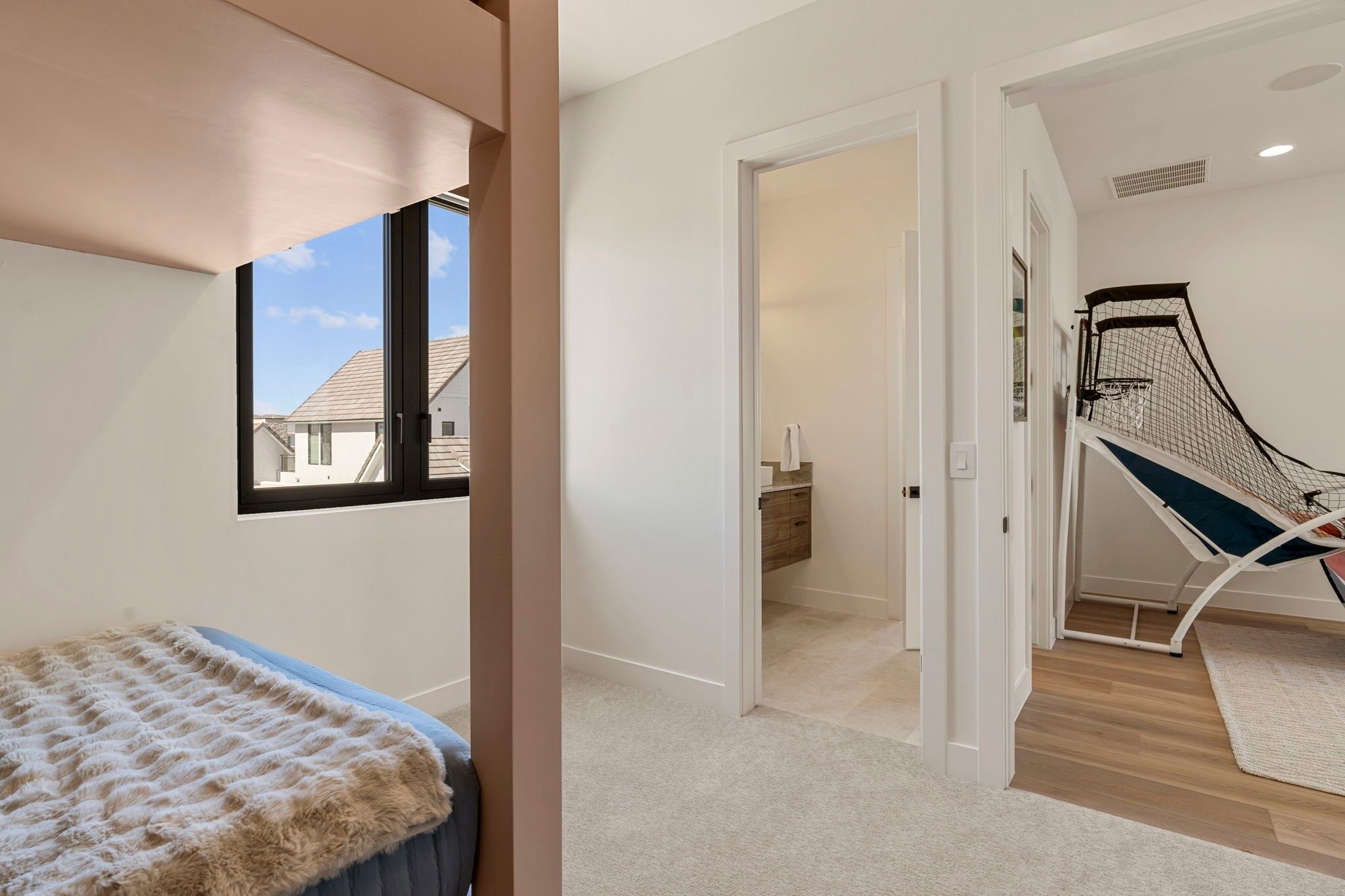 Quarto com cama, janela, porta para um banheiro e uma cadeira suspensa.