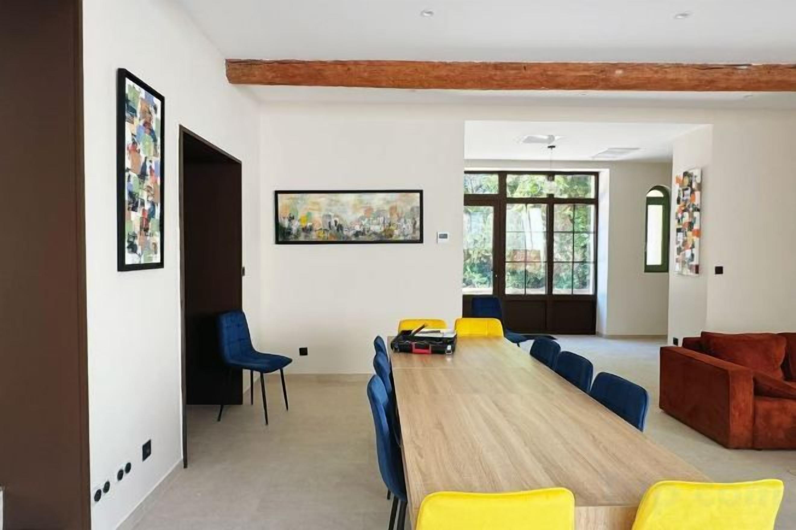 Een vergaderruimte met een lange tafel, blauwe stoelen en een rode bank.
