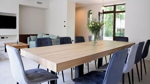 Een moderne eethoek met een houten tafel en grijze stoelen met bekleding.
