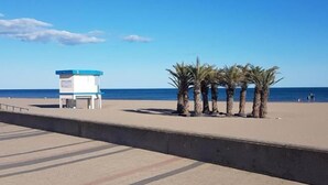 Een redderstoren en palmbomen aan het strand.
