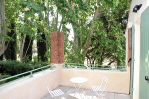 Un balcon avec un pilier en briques, deux chaises blanches et une table.