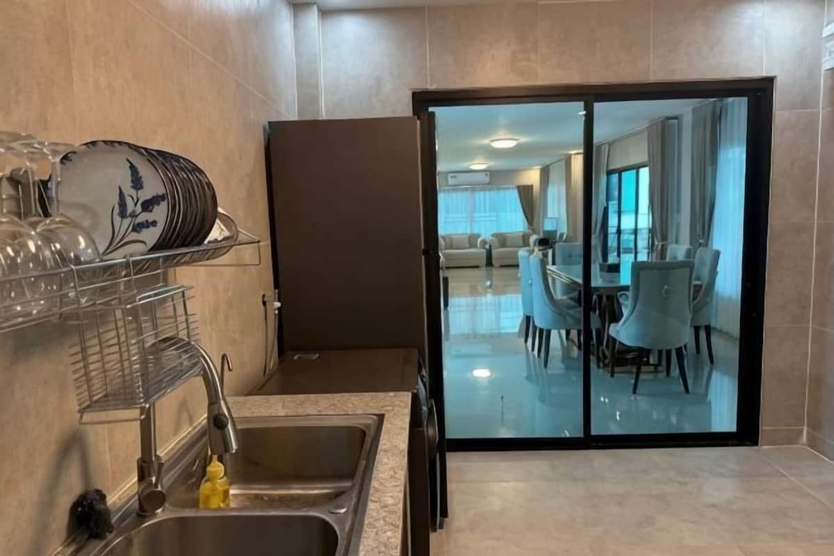 A modern kitchen with a dish rack, a sink, and a sliding glass door leading to a dining area with a table and chairs.