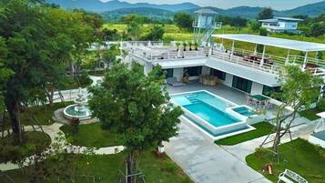 A hotel with a swimming pool, outdoor seating, and a view of the mountains.