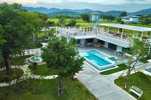 A hotel with a swimming pool, outdoor seating, and a view of the mountains. - The Pano Hill (Pak Chong)