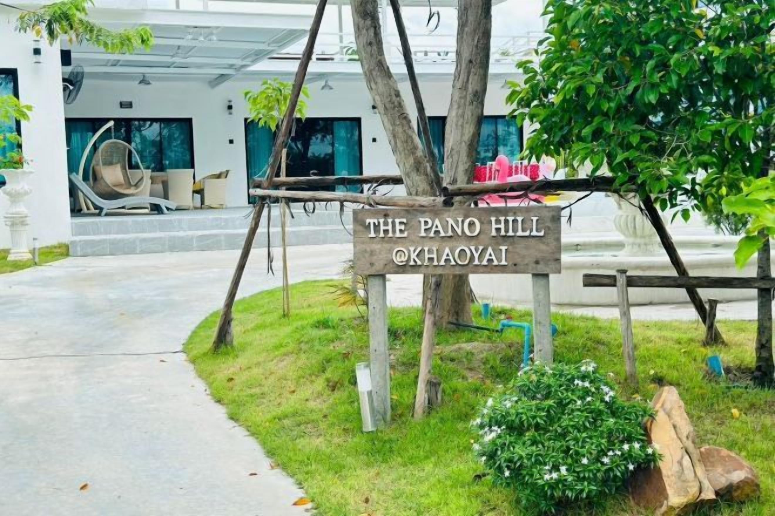 A sign for 'The Pano Hill' hotel with a wooden structure and a view of the hotel entrance.