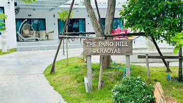 A sign for 'The Pano Hill' hotel with a wooden structure and a view of the hotel entrance.