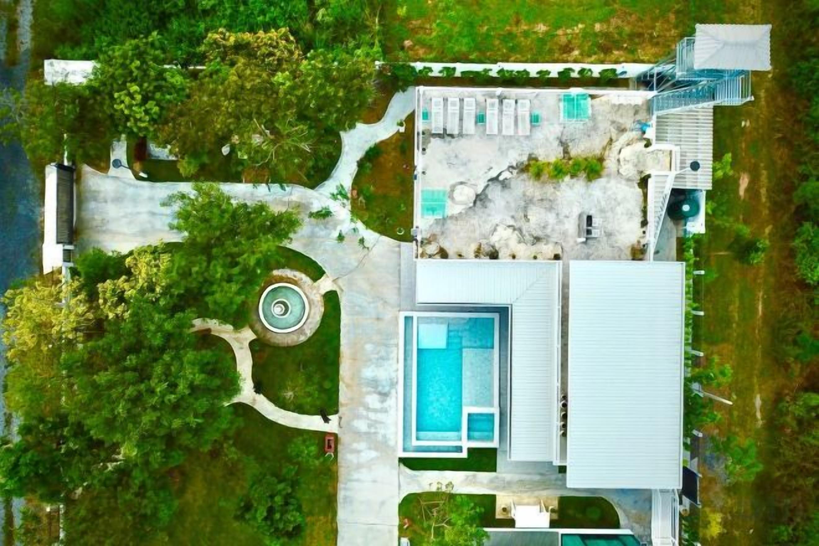 Vue aérienne d’une propriété dotée d’une piscine, d’une allée circulaire et d’un espace paysager agrémenté d’arbres.