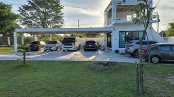 A modern building with a covered parking area and several cars parked in front.