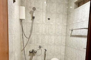 Et badeværelse med brusebad, toilet og håndklædestang.