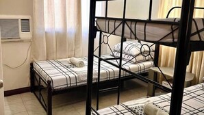 A bunk bed room with a window, curtains, and an air conditioning unit. - Cranberry's 2Br Unit nr Convention Center #1 (Iloilo City)