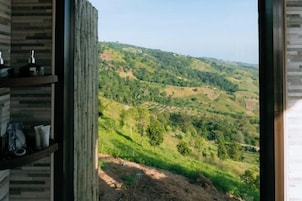 Une chambre avec vue sur un paysage vallonné.
