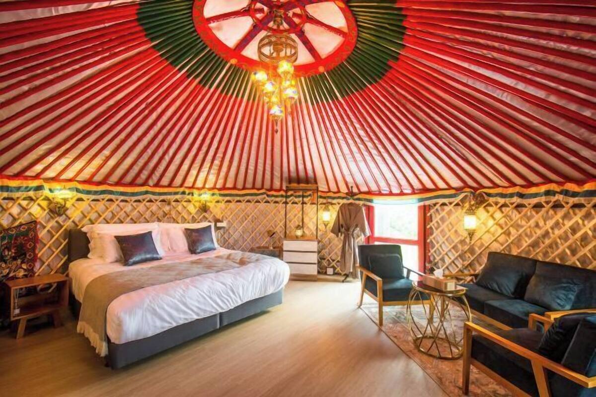 A yurt with a bed, a chair, and a sofa.
