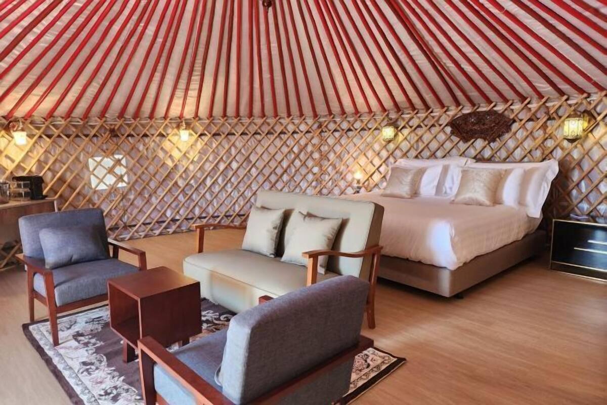 A room with a bed, two armchairs, a sofa, and a small table.