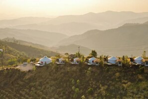 Varias edificaciones con forma de cúpula en una colina, con vistas a montañas distantes.