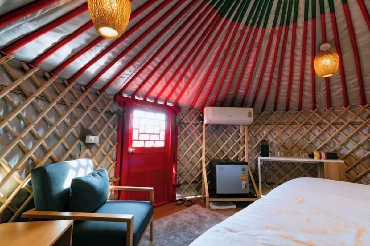 A cozy, well-lit tent with a bed, a desk, and a chair.