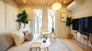 A cozy living room with a sofa, a coffee table, a TV, and a wooden ceiling. - Infinity Grove in Ikebukuro・ZHUOJU (Tokyo)