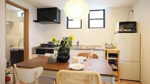 A compact kitchen with a dining table, chairs, a microwave, and a sink. - Infinity Grove in Ikebukuro・ZHUOJU (Tokyo)