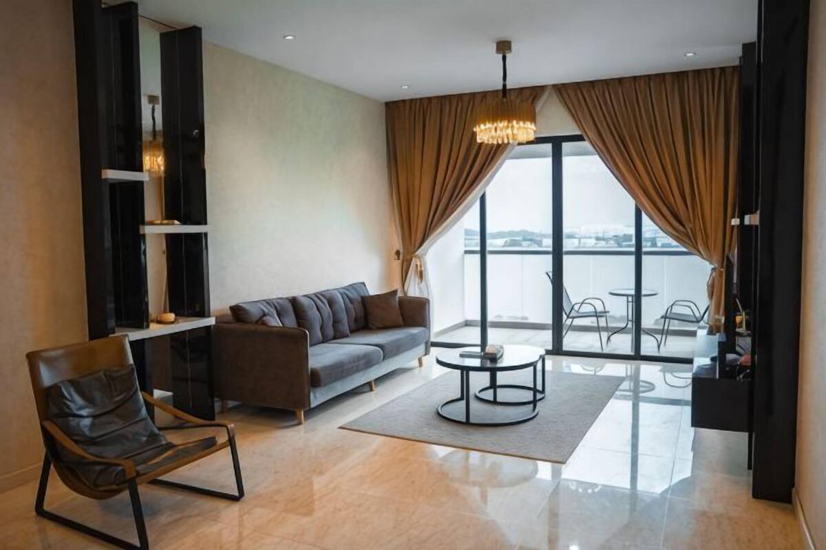Un salon moderne avec un canapé, un fauteuil, une table basse et une vue sur l’extérieur.