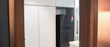 A kitchen with a black refrigerator, white cabinets, and a wooden door frame.