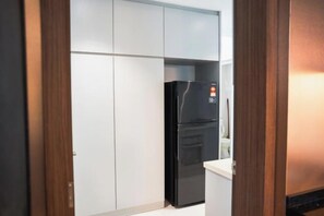 A kitchen with a black refrigerator, white cabinets, and a wooden door frame. - The Marina View Johor Bahru (Plentong)