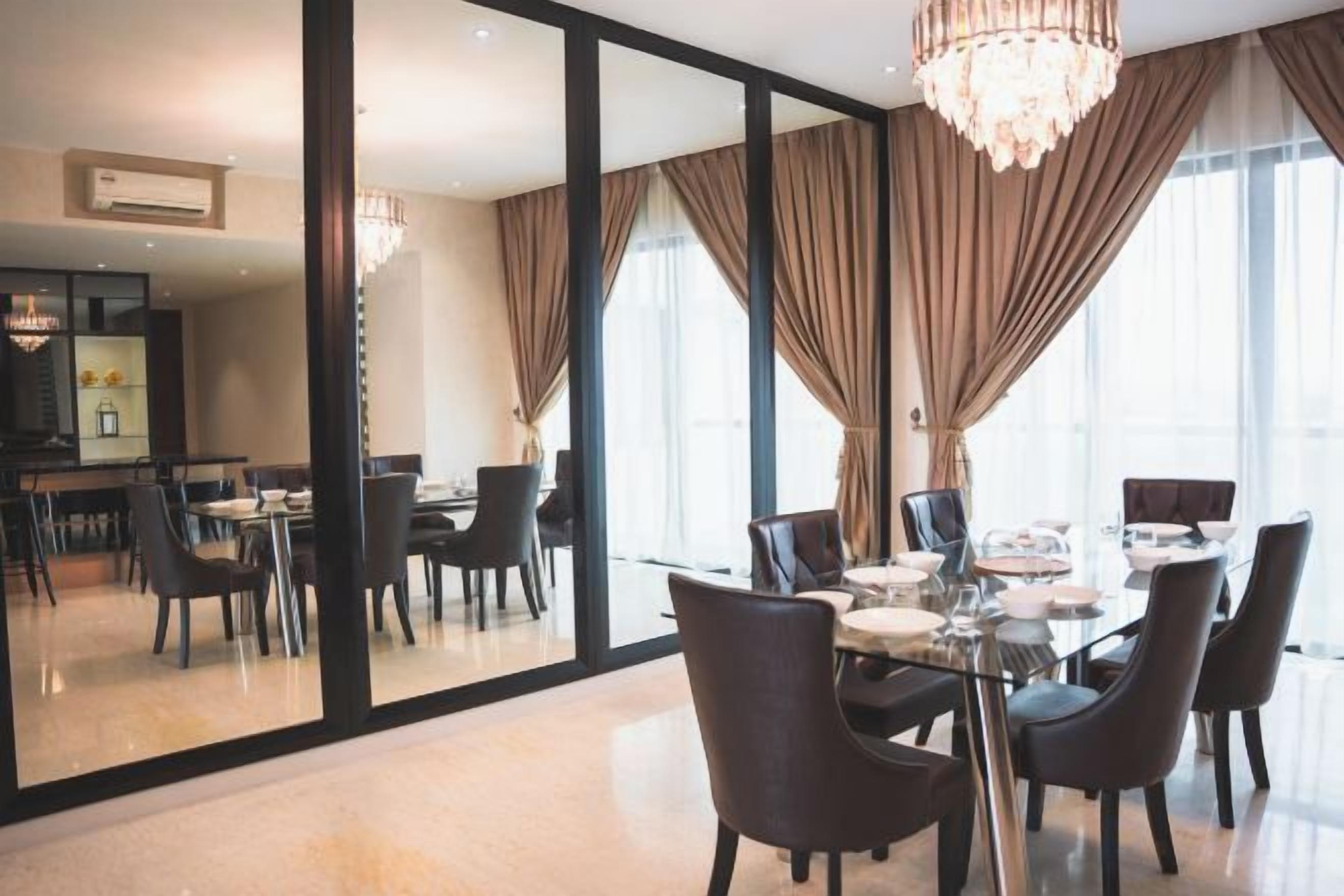 Een eetgedeelte met een glazen tafel, stoelen en een kroonluchter.