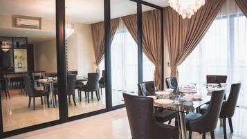 Een eetgedeelte met een glazen tafel, stoelen en een kroonluchter.