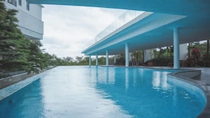 Une piscine dotée d’une architecture moderne, entourée de verdure et agrémentée d’une allée couverte.