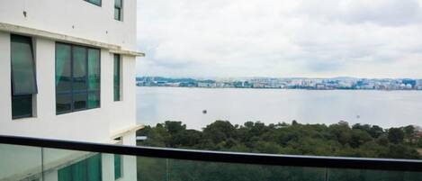 A high-rise building with a view of a body of water and a distant cityscape.