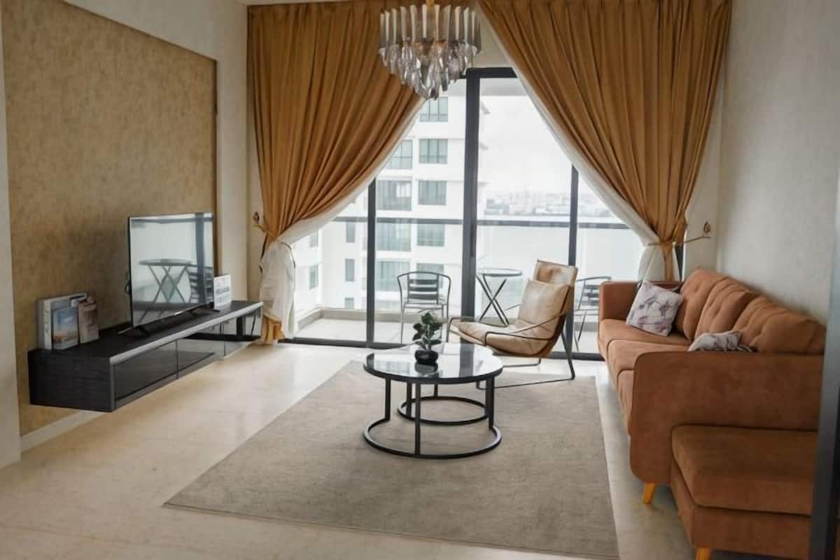 Un salon moderne avec un canapé, une table basse, un téléviseur et un balcon offrant une vue agréable.