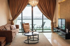 A modern living room with a sofa, coffee table, and TV, overlooking a body of water. - The Marina View Johor Bahru (Plentong)