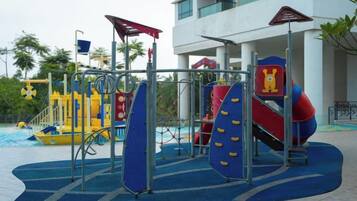 A playground with slides and climbing structures, located in an outdoor area with a building in the background.