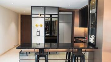 A modern kitchen with a black countertop, two bar stools, and a built-in refrigerator.