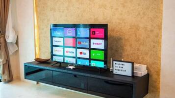 Ein Flachbildfernseher auf einer schwarzen Unterhaltungsecke mit einem Schild, auf dem 'WILLKOMMEN IN UNSEREM HOTEL' steht.