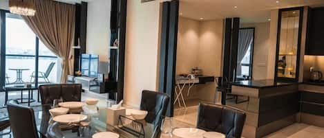A modern dining area with a glass table, black chairs, and a view of the city.