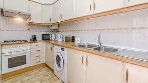 A compact kitchen with white cabinets, a washing machine, a microwave, a toaster, and a sink. - #341 Casa da Guida | Central & Cozy (Albufeira)